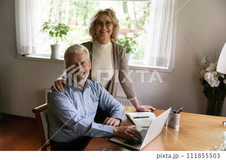 Portrait of happy senior spouses managing family business using laptop 111855503