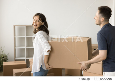 Joyful young married couple carrying large moving box Joyful young married couple carrying large moving box 111855590
