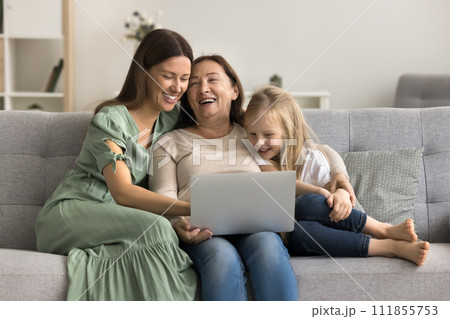 Cheerful mom, grandma and child using laptop together on sofa Cheerful mom, grandma and child using laptop together on sofa 111855753