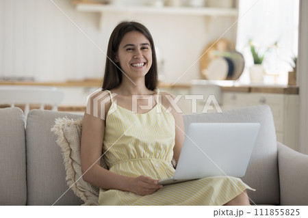 Smiling woman relax at home looking at camera use laptop Smiling woman relax at home looking at camera use laptop 111855825