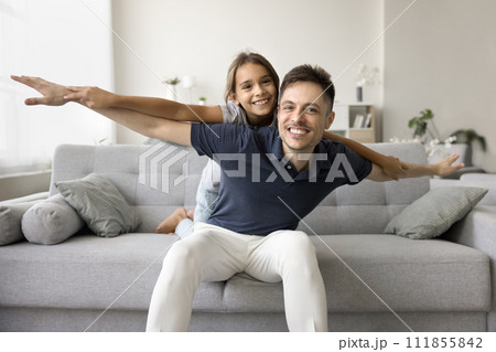 Cheerful playful daddy piggybacking little daughter kid with open hands 111855842