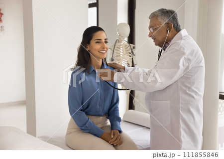 Older Indian doctor man checking heartbeat rate of young patient Older Indian doctor man checking heartbeat rate of young patient 111855846