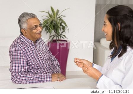 Happy senior Indian patient consulting therapist doctor in clinic office 111856133