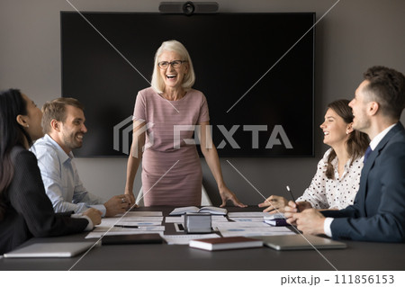 Cheerful senior leader woman and younger diverse employees having fun 111856153