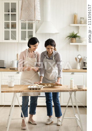 Older mum her young adult daughter kneading dough enjoy talk 111856157