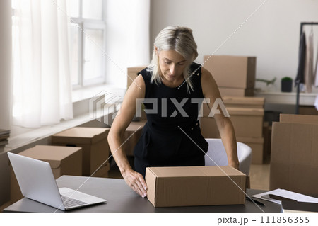Businesswoman packing cardboard box, prepare parcel for dispatch Businesswoman packing cardboard box, prepare parcel for dispatch 111856355