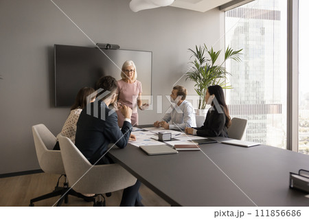 Mature senior business leader woman talking to group of colleagues Mature senior business leader woman talking to group of colleagues 111856686