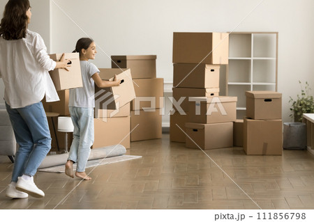 Pretty daughter and mom carrying moving boxes in new apartment Pretty daughter and mom carrying moving boxes in new apartment 111856798