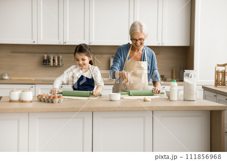 Cheerful grandma and positive granddaughter girl cooking pastry food 111856968
