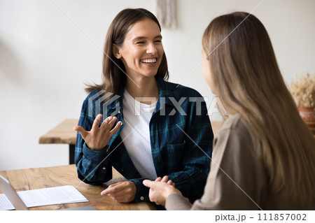 Cheerful young female managers talking at office workplace table 111857002