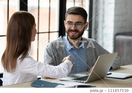 Grateful client shaking hands with bank worker in modern office 111857530