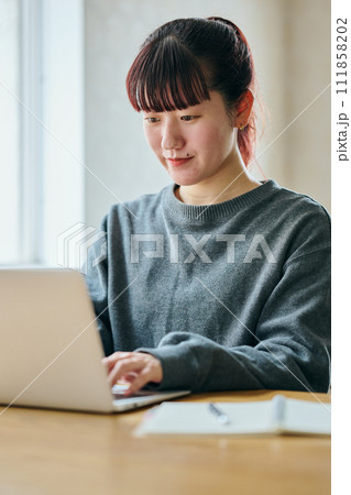 パソコンをタイピングする若い女性 パソコンをタイピングする若い女性 111858202