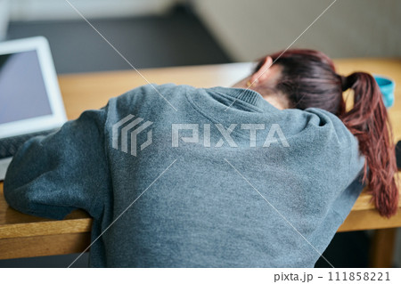 デスクで塞ぎ込む憂鬱そうな表情の若い女性 111858221