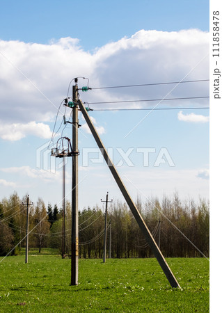 Poles with electrical wires in a green field 111858478