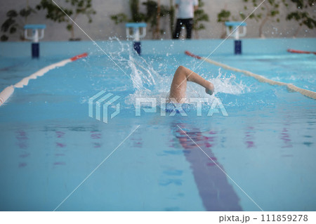 An athlete is swimming in the sports pool. An athlete is swimming in the sports pool. 111859278