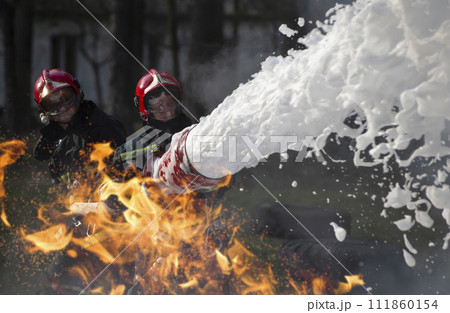 Firefighters extinguish a fire. Lifeguards with fire hoses in smoke and fire. 111860154