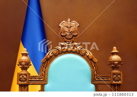 Constitutional Court of Ukraine law justice system. Empty chair judge Ukraine flag in courtroom background. Trial court scales of justice symbol Ukraine justice reform Constitutional Court of Ukraine law justice system. Empty chair judge Ukraine flag in courtroom background. Trial court scales of justice symbol Ukraine justice reform 111860313