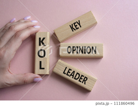 KOL - Key Opinion Leader symbol. Concept word KOL on wooden blocks. Businessman hand. Beautiful pink background. Business and KOL concept. Copy space. KOL - Key Opinion Leader symbol. Concept word KOL on wooden blocks. Businessman hand. Beautiful pink background. Business and KOL concept. Copy space. 111860496