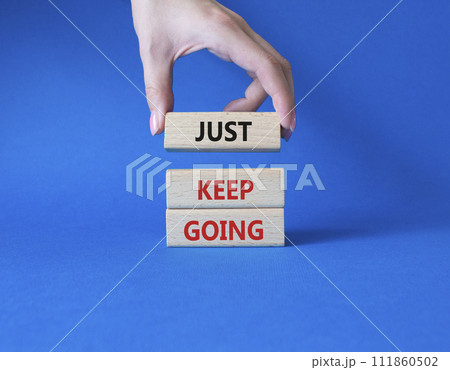 Just keep going symbol. Concept words Just keep going on wooden blocks. Beautiful blue background. Businessman hand. Business and Just keep going concept. Copy space. 111860502