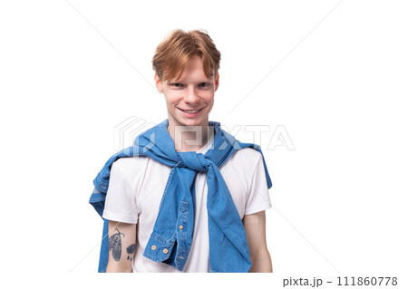 young positive red-haired man with a short haircut with a tattoo on his arms wearing a white t-shirt young positive red-haired man with a short haircut with a tattoo on his arms wearing a white t-shirt 111860778