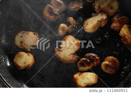 Frying forest mushrooms boletus served in iron cast pan. Vegetarian autumn food concept. Food plating and aesthetic concept. Frying forest mushrooms boletus served in iron cast pan. Vegetarian autumn food concept. Food plating and aesthetic concept. 111860951
