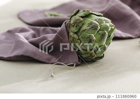 Fresh artichoke in purple linen bag. Healthy food cooking ingredients background with fresh vegetables 111860960