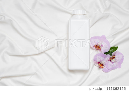 Liquid laundry detergent or fabric softener on bedding, orchid flowers, top view Liquid laundry detergent or fabric softener on bedding, orchid flowers, top view 111862126