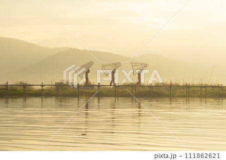 Burmese fisherman casting or throwing a net for catching freshwater fish in Unle lake, natural river in Asia in Myanmar. People lifestyle. 111862621