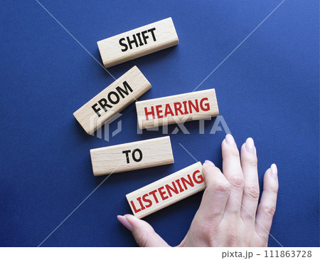 Listening symbol. Wooden blocks with words Shift from Hearing to Listening. Businessman hand. Beautiful deep blue background. Business and Listening concept. Copy space. 111863728