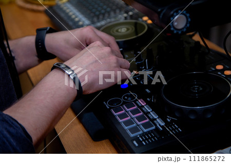 A DJ in a nightclub at the control panel adjusts the music. Music is playing, creating an atmosphere. High quality photo A DJ in a nightclub at the control panel adjusts the music. Music is playing, creating an atmosphere. High quality photo 111865272