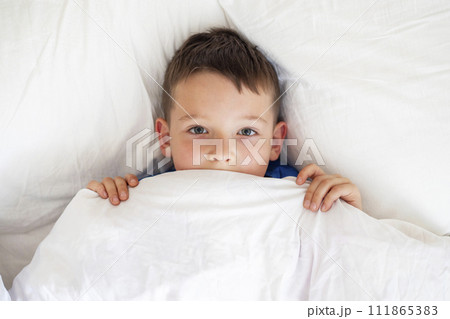 Young Boy Peeking from White Bedding 111865383