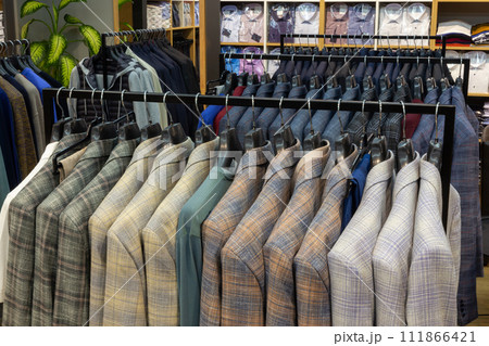 A row of men's suits, jackets hanging on a rack for display. A row of men's suits, jackets hanging on a rack for display. 111866421
