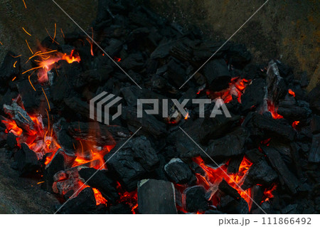 Coals with sparks in a huge old metal grill Coals with sparks in a huge old metal grill 111866492