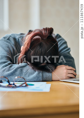 デスクで塞ぎ込む若い女性 111867439