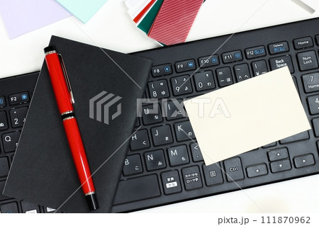 黒いキーボードの上に黒い手帳と赤いペン 無地のカード 付箋 黒いキーボードの上に黒い手帳と赤いペン 無地のカード 付箋 111870962