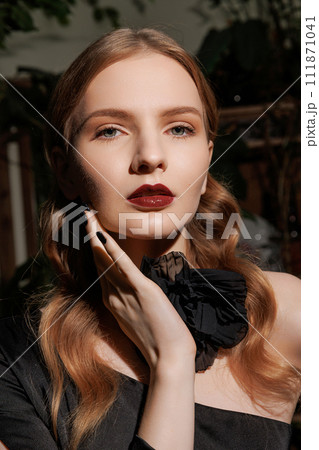 Portraint woman with wavy hair, dark attire. 111871041