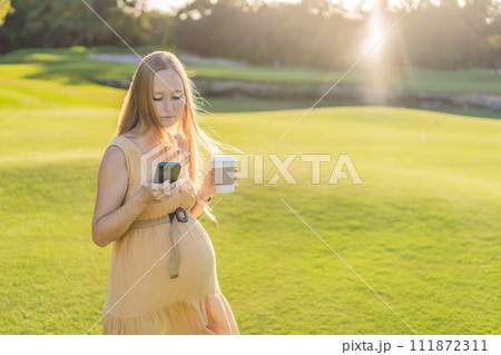 pregnant woman enjoys a cup of coffee outdoors, blending the simple pleasures of nature with the comforting warmth of a beverage during her pregnancy pregnant woman enjoys a cup of coffee outdoors, blending the simple pleasures of nature with the comforting warmth of a beverage during her pregnancy 111872311