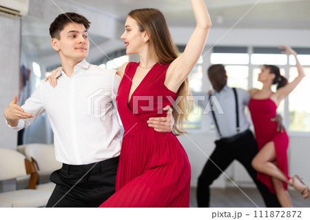 Guy dancing bachata with female partner in red in choreography studio Guy dancing bachata with female partner in red in choreography studio 111872872