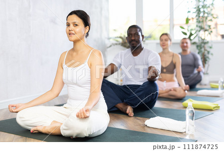 Woman making yoga meditation in lotus pose for health care and wellness with group in fitness club Woman making yoga meditation in lotus pose for health care and wellness with group in fitness club 111874725