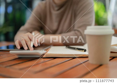 A close-up shot of a woman using a calculator, calculating her salary and monthly expenses. 111877743