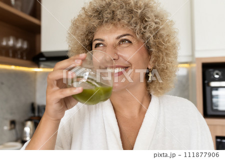 Smiling Woman Enjoying a Healthy Green Juice in Modern Kitchen 111877906