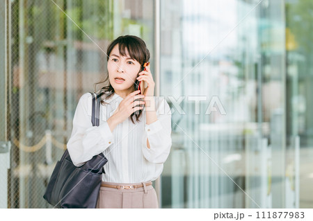 オフィスビルでスマホで通話しながら歩くビジネスウーマン(驚く・ショック・びっくり・トラブル) オフィスビルでスマホで通話しながら歩くビジネスウーマン(驚く・ショック・びっくり・トラブル) 111877983