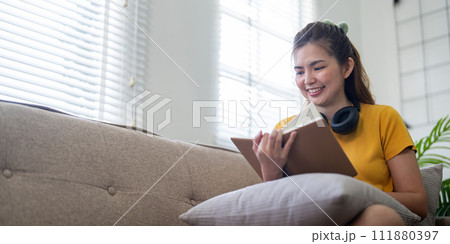 Young pretty woman siting on sofa and reading a book enjoys of rest. relaxing at home 111880397