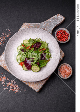 Delicious fresh salad with arugula, spinach, cucumber and cherry tomatoes in a ceramic plate 111880966