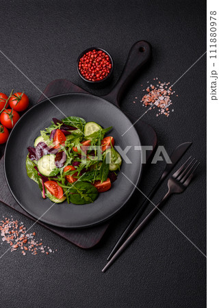 Delicious fresh salad with arugula, spinach, cucumber and cherry tomatoes in a ceramic plate 111880978