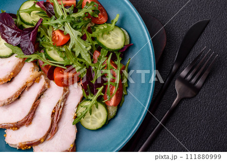 Delicious dietary salad with arugula, cucumber and cherry tomatoes and chicken breast slices 111880999