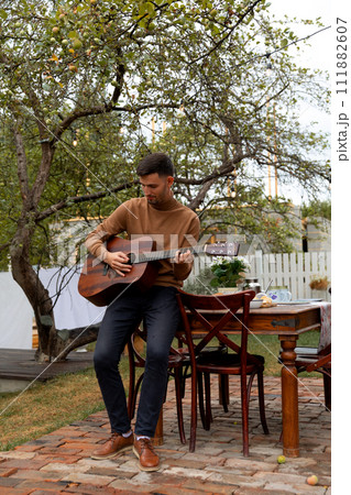 young man sits at the table and plays the guitar 111882607