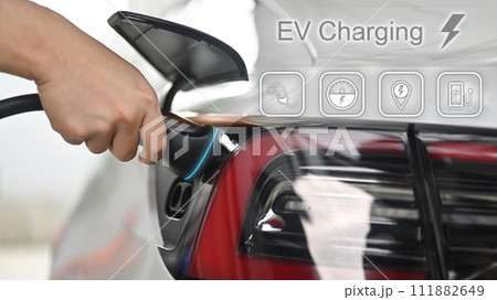 Unrecognizable man plugging electric car from charging station. Alternative clean energy concept 111882649