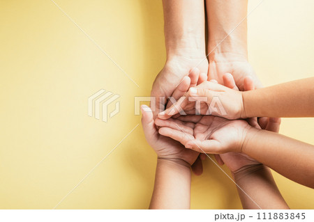 A touching gesture captured in a studio top view shot, family hands stacked on an isolated background. Parents and children hold an empty space reflecting support and love. A touching gesture captured in a studio top view shot, family hands stacked on an isolated background. Parents and children hold an empty space reflecting support and love. 111883845