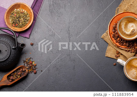A tantalizing display of roasted coffee beans and dry tea leaves, accompanied by an espresso coffee cup and a teapot 111883954